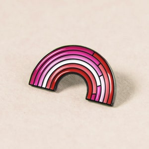 May include: An enamel pin featuring a rainbow design in the colours of the lesbian pride flag. The pin is made of metal and has a black outline.