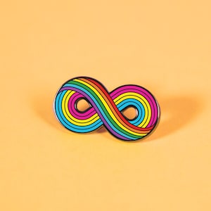 Puede incluir: Un pin con el símbolo del infinito en forma de arcoíris con un contorno negro. El pin está sobre un fondo naranja claro.