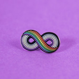 May include: A rainbow infinity symbol pin on a purple background.