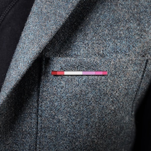 May include: A grey blazer with a small, colourful pin in the pocket. The pin has red, white and pink stripes.