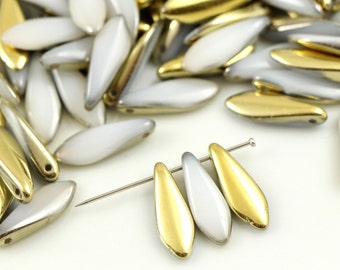 May include: A group of white and gold glass beads in a teardrop shape. The beads are scattered on a white surface. A close-up shows three beads strung on a wire.
