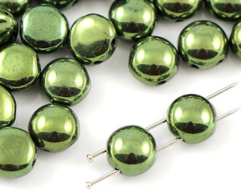 May include: A pile of green glass beads with a metallic sheen. The beads are round and have a slightly flattened shape. They are arranged in a random pattern.