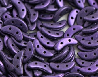 May include: A close-up of a pile of small, crescent-shaped beads. The beads are a deep purple color with a metallic sheen.