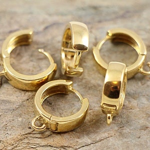 Könnte beinhalten: Vier goldfarbene Ohrringe aus Metall mit Scharnierverschluss. Die Ohrringe haben einen Durchmesser von etwa 2,5 cm.