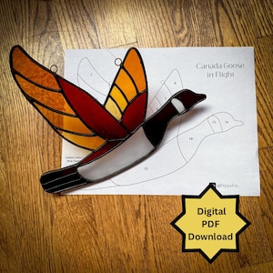 May include: A stained glass Canada Goose in flight pattern with numbered pieces. The pattern is printed on white paper with the text "Canada Goose in Flight" and "@Peppyfox". A digital PDF download is indicated by a yellow star with the text "Digital PDF Download".