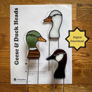 May include: Three stained glass bird heads including a mallard duck, a white goose, and a Canada goose, each with a metal stake. The paper pattern behind them reads Geese & Duck Heads and Digital Download, with instructions for assembly.