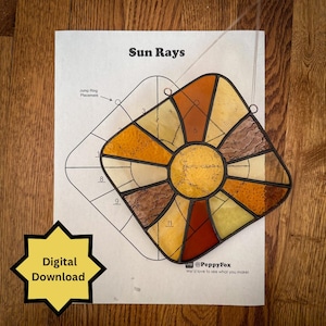 May include: A stained glass suncatcher with a sunburst design in shades of yellow, orange, and brown. The suncatcher is placed on a paper with the text "Sun Rays" and a diagram. A yellow starburst graphic reads "Digital Download".