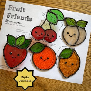 May include: Five stained glass fruit ornaments featuring a strawberry, cherries, a peach, an orange, and a lemon, each with a smiling face. The ornaments are displayed on a printed pattern sheet titled Fruit Friends with text and diagrams.