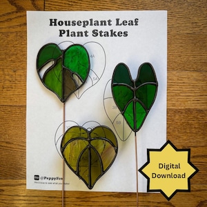 Puede incluir: Tres estacas de vidrio manchado para plantas con forma de hojas, con tallos de cobre, se muestran sobre un papel blanco con el texto "Houseplant Leaf Plant Stakes". Las hojas son de diferentes tonos de verde y amarillo. Un gráfico de estrella amarilla dice "Digital Download".
