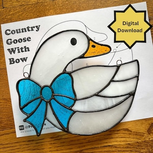 May include: Stained glass goose with a blue bow. The goose is white with a yellow beak and black eye. The design is on a paper with the text "Country Goose With Bow" and a "Digital Download" graphic.