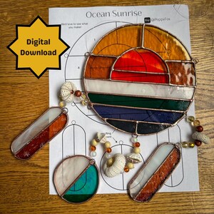 Op de afbeelding: Een digitaal downloadpatroon voor een gebrandschilderd zonenvanger met een kleurrijk zonsondergangsontwerp. Het patroon bevat een cirkel met een rood, oranje, geel, wit, groen, blauw en zwart ontwerp. Het patroon bevat ook twee kleinere rechthoekige stukken met een wit, oranje en bruin ontwerp. Het patroon is afgedrukt op wit papier met de woorden "Ocean Sunrise" en "Digitale Download" afgedrukt op de pagina.