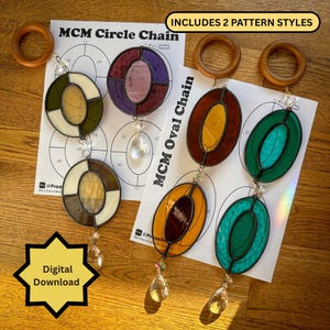 May include: Four stained glass suncatchers with oval shapes and wooden rings, displayed on printed pattern sheets labeled MCM Circle Chain and MCM Oval Chain. The glass pieces feature various colors including green, brown, purple, yellow, and teal, with clear crystal prisms hanging from the bottom of each chain.