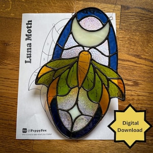 May include: Stained glass Luna Moth design with a blue, green, yellow, and white color scheme. The design is on a white paper with the text "Luna Moth" and "Digital Download". The Etsy shop name "@PeppyFox" is also visible.