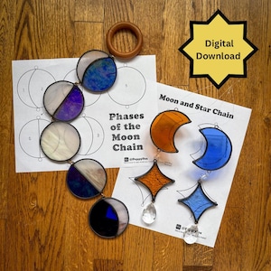 May include: A collection of stained glass moon phase and star chain ornaments, with a wooden ring and printed templates. The ornaments feature various colors, including blue, purple, and orange. The text "Phases of the Moon Chain" and "Moon and Star Chain" are visible.
