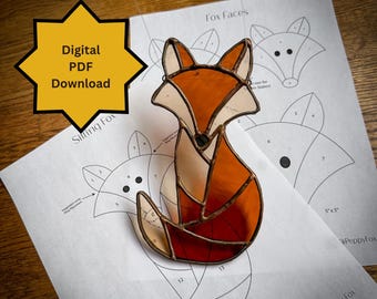 May include: A digital PDF download pattern for a stained glass fox. The pattern includes a sitting fox and two fox faces. The fox is orange and brown with black eyes. The pattern is 5 inches by 5 inches.