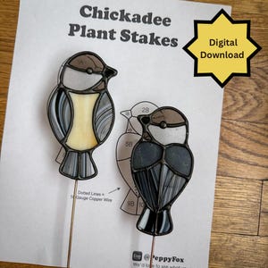 May include: Two stained glass chickadee plant stakes. One has a yellow center, the other a dark grey center. The text "Chickadee Plant Stakes" and "Digital Download" are visible. The stakes are on copper wire.