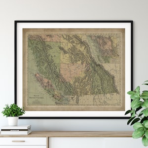 May include: Vintage map of British Columbia, Canada, printed on aged paper with a black frame. The map shows the geographical features of the region, including mountains, rivers, and lakes. The map is in shades of green, brown, and blue.