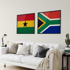 May include: Two framed flags hanging on a white wall. The flag on the left is the flag of Ghana, with a black star on a yellow background, red and green stripes. The flag on the right is the flag of South Africa, with red, yellow, green, blue, and black stripes.