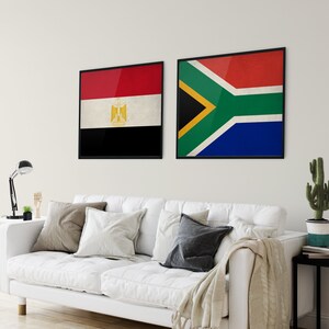 May include: Two framed flags hanging on a white wall. The flag on the left is the flag of Egypt, with red, white, and black colors. The flag on the right is the flag of South Africa, with red, yellow, green, blue, and black colors.