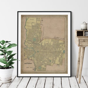 May include: An antique map of Columbus, Ohio, printed on aged paper with a beige background and green and brown lines. The map is framed in a black frame.