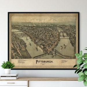 May include: An antique map of Pittsburgh, Pennsylvania from 1902. The map shows the city's layout with rivers, bridges, and buildings. The map is printed in brown, green, and black ink on a cream-coloured background.