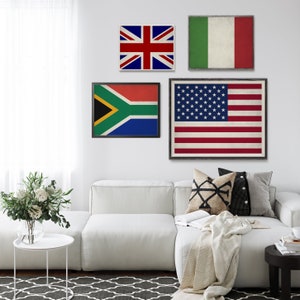 May include: Three framed flags hanging on a white wall above a white couch. The flags are the American flag, the South African flag, and the British flag. The flags are all in a vintage style with a distressed look.