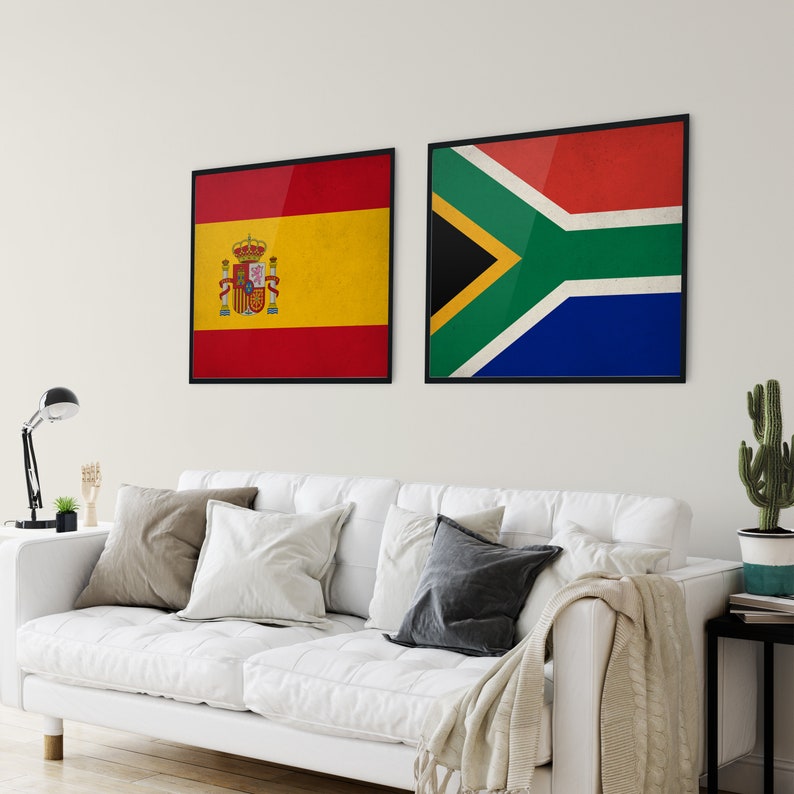 May include: Two framed wall art pieces featuring the flags of Spain and South Africa. The Spanish flag is red and yellow with a coat of arms. The South African flag is red, green, blue, black, and yellow. Both are in black frames.