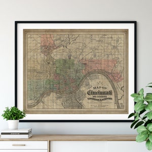 May include: An antique map of Cincinnati, Ohio, and its suburbs, Covington and Newport, printed on aged paper with a grid pattern. The map shows the city's streets, rivers, and landmarks. The title "MAP OF CINCINNATI AND SUBURBS COVINGTON & NEWPORT" is printed in a decorative font.