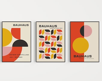 May include: Three Bauhaus style posters with geometric shapes in red, yellow, black, and pink. The text on the posters reads "Bauhaus", "Entwurf Ausstellung Juli - Oktober", "Ausstellung 1923", and "Revolution des Designs".