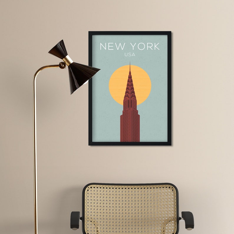 May include: A black framed poster with a minimalist illustration of the Chrysler Building in New York City, USA. The building is red and the background is blue with a yellow sun.