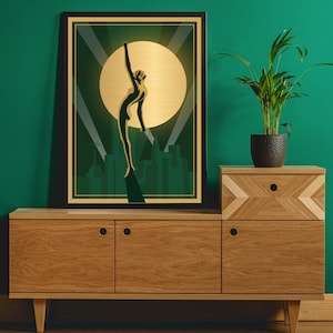 Peut inclure: Une estampe encadr&eacute;e avec une silhouette dor&eacute;e d'une femme levant les bras contre un fond vert et or. La femme se tient devant un horizon urbain.