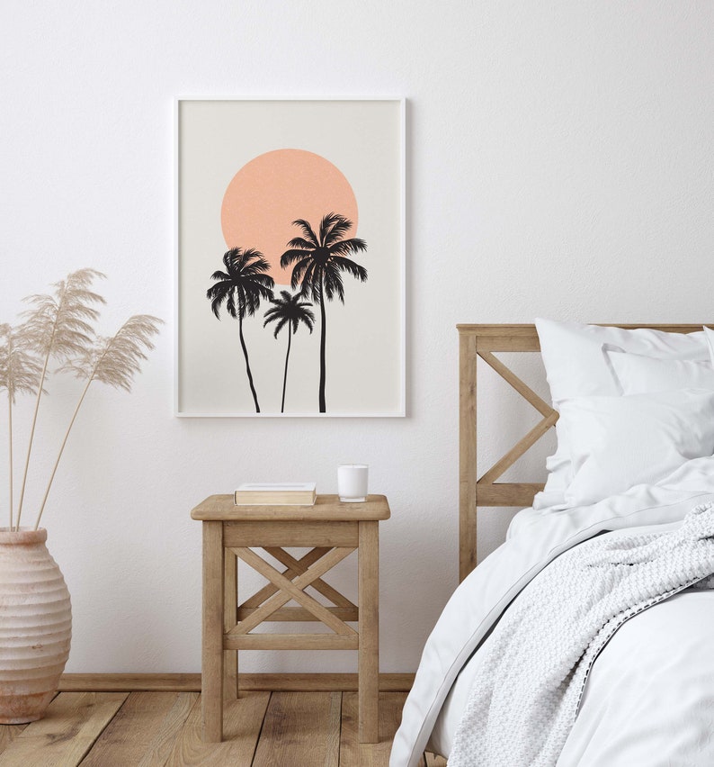 May include: A framed print with a minimalist design featuring three palm trees silhouetted against a peach-colored sun on a light beige background.