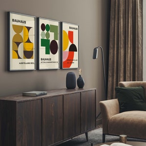 May include: Three framed prints with geometric designs in red, yellow, green, and black. The prints are titled "Bauhaus" and feature the text "Ausstellung 1923" and "Sommer Ausstellung Juli - Oktober".