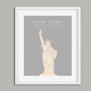May include: A framed print with a grey background and a white outline. The print features a line drawing of the Statue of Liberty in beige. The text "NEW YORK" and "UNITED STATES OF AMERICA" is printed in white at the top of the print.