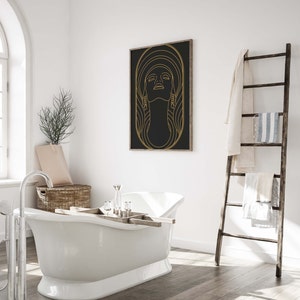 Puede incluir: Una ba&ntilde;era blanca con una bandeja de madera y una impresi&oacute;n enmarcada en dorado de la cara de una mujer sobre un fondo negro. La impresi&oacute;n tiene un contorno dorado y la cara de la mujer mira hacia arriba.