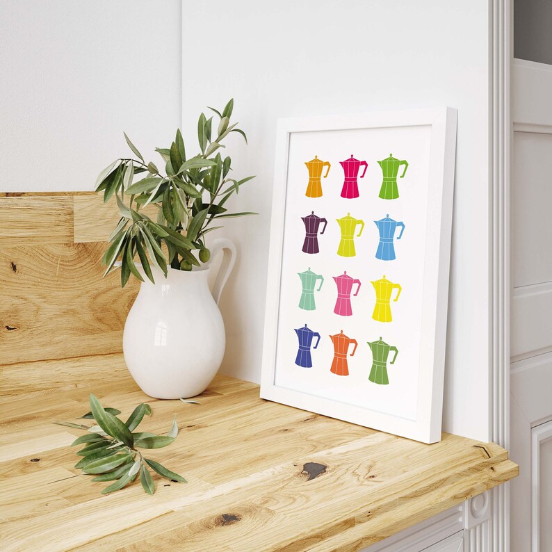 May include: A white framed print with a colorful design of 12 espresso makers in various colors, including red, orange, yellow, green, blue, purple, and pink.