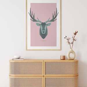 May include: A geometric deer head print in shades of gray and teal on a light pink background. The print is framed in natural wood and hangs above a light wood cabinet with woven rattan doors.