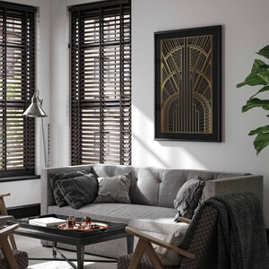 May include: A gray sofa with black throw pillows sits in a living room with brown wood blinds, a coffee table with a tray of glasses, and a black framed print with a gold geometric design.