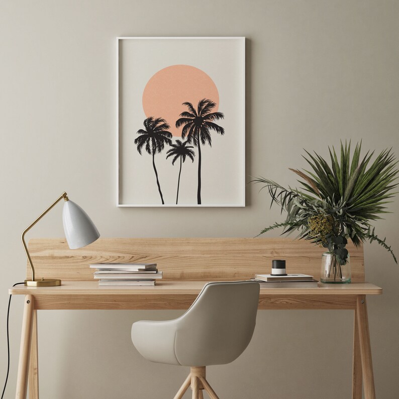 May include: A framed print of a minimalist design featuring three palm trees silhouetted against a peach-colored sun on a light beige background.