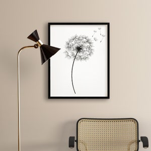 May include: Black and white line art print of a dandelion with seeds blowing in the wind, framed in a black frame.