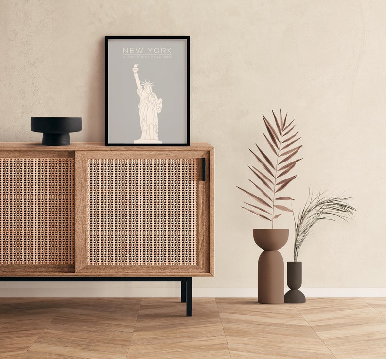 May include: A wooden cabinet with two sliding doors, a black top, and a framed print of the Statue of Liberty with the text "NEW YORK, UNITED STATES OF AMERICA".