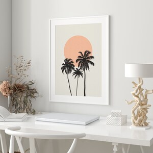 May include: A framed print with a minimalist design featuring three palm trees silhouetted against a peach-colored sun on a beige background.