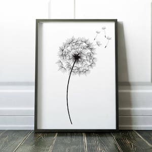 May include: Black and white line art print of a dandelion with seeds blowing in the wind. The print is framed in a black frame and is hanging on a white wall.