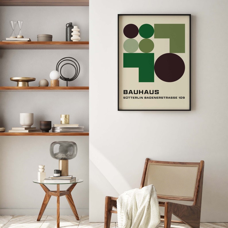 May include: A black framed poster with a geometric design in shades of green and brown. The poster has the text "BAUHAUS" and "S&Uuml;TTERLIN BADENSTRASSE 109" printed on it.