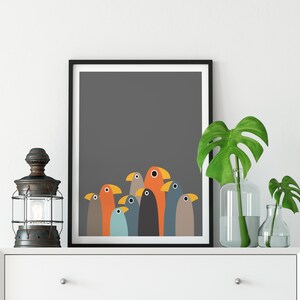 K&ouml;nnte beinhalten: Ein gerahmter Druck eines farbenfrohen abstrakten Kunstwerks mit einer Gruppe stilisierter V&ouml;gel in Orange-, Blau-, Grau- und Braunt&ouml;nen vor einem dunkelgrauen Hintergrund.