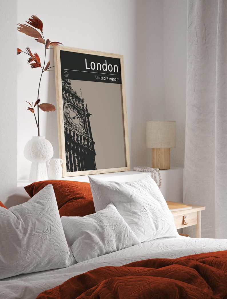 Peut inclure: Une affiche en noir et blanc encadr&eacute;e avec une photo du Big Ben &agrave; Londres, en Angleterre. L'affiche porte le texte "London" et "United Kingdom". L'affiche est accroch&eacute;e &agrave; un mur blanc au-dessus d'un lit avec une literie blanche et rouge.