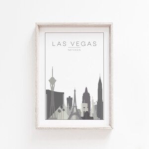 K&ouml;nnte beinhalten: Ein gerahmter Druck einer grauen Skyline von Las Vegas, Nevada. Der Druck zeigt ikonische Geb&auml;ude wie den Stratosphere Tower und das Wynn Hotel.