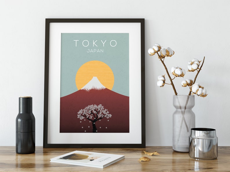 Puede incluir: Una impresi&oacute;n enmarcada con un dise&ntilde;o minimalista que presenta el Monte Fuji, un &aacute;rbol de cerezo en flor y un sol amarillo sobre un fondo azul y rojo. El texto "TOKYO JAP&Oacute;N" est&aacute; en la parte superior de la impresi&oacute;n.