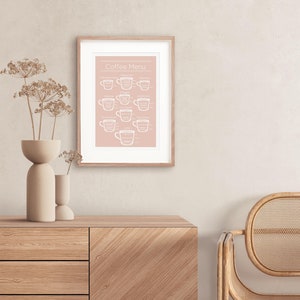 May include: A framed print with a pink background and white text that reads "Coffee Menu". The print features illustrations of different types of coffee drinks, including cappuccino, latte, espresso, and macchiato.