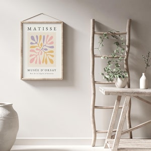 May include: A framed print with a colorful abstract design in pink, yellow, and purple. The print has the text "MATISSE" and "MUS&Eacute;E D'ORSAY" with the address "Rue de la L&eacute;gion d'honneur".
